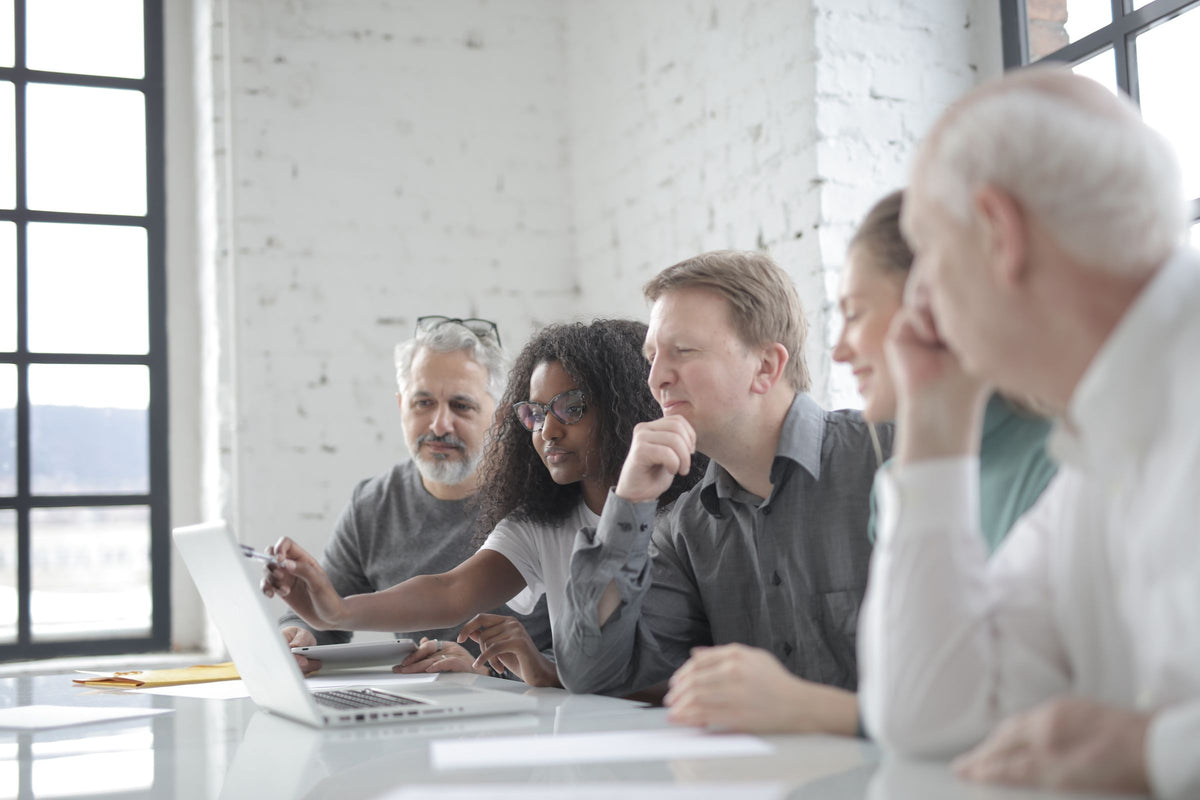 Team collaborating around a laptop representing Microsoft 365 Business Basic