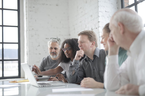 Team collaborating around a laptop representing Microsoft 365 Business Basic