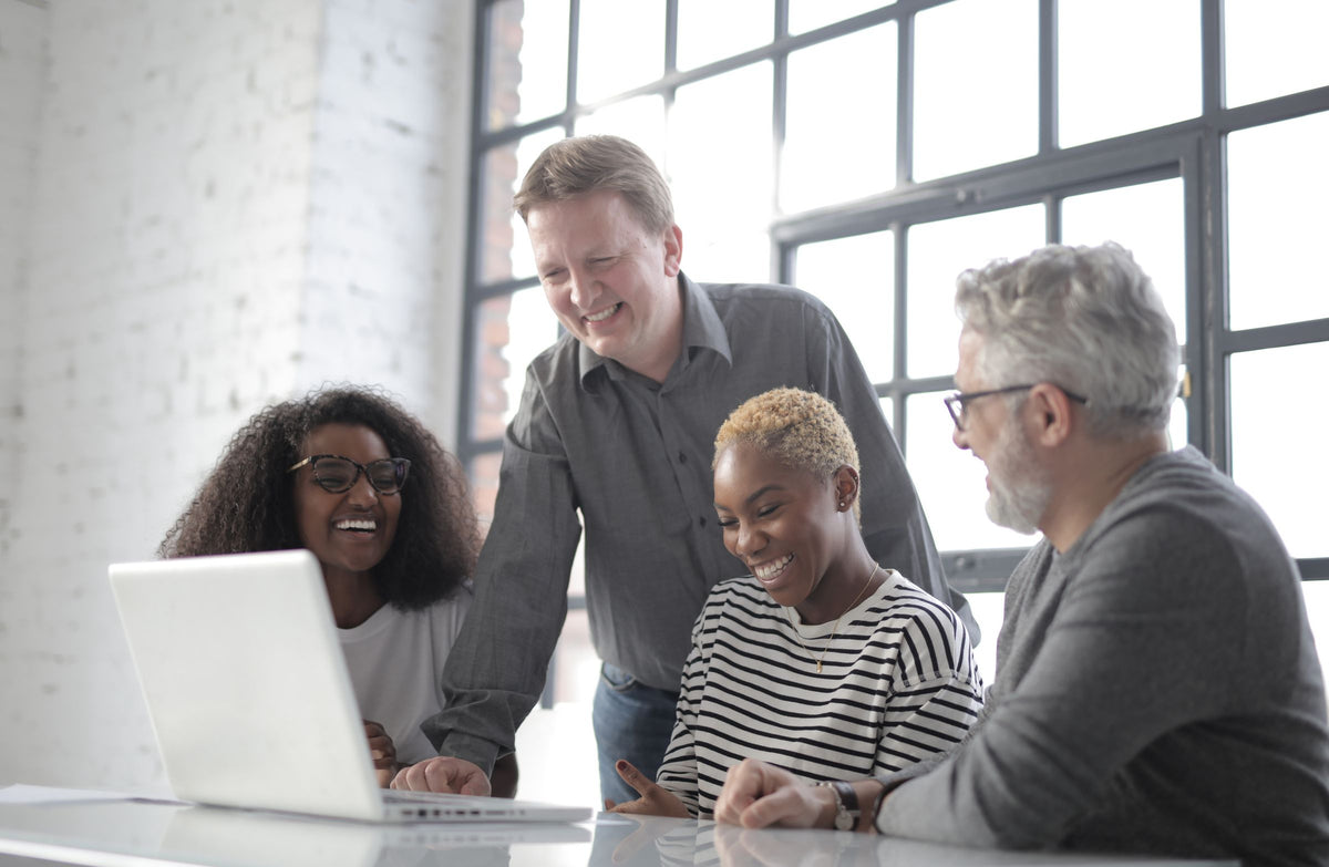 Colleagues smiling while working together on a laptop